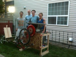 Mike Johnson (centre-right) stands behind Operation Fruit Rescue Edmonton's pedal-powered apple crusher. Source: OFRE